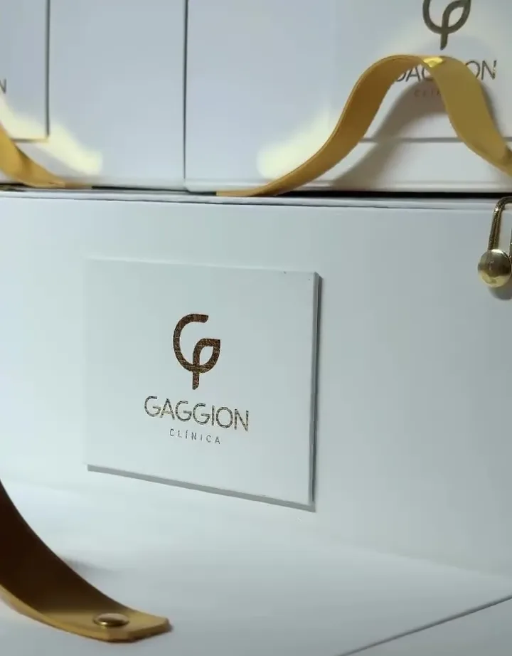 Caixa branca da Clínica Gaggion com alça e ferragem douradas